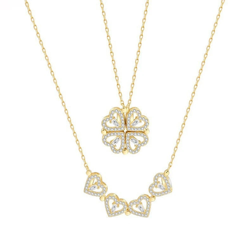 gold layered necklace — one chain with a four-leaf clover pendant and the other with small heart-shaped pendants.